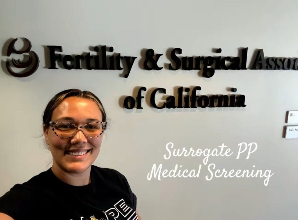 A happy person stands in front of a clinic sign, representing Babytree Surrogacy’s medical screening for surrogates. Alt text: Person at clinic showing Babytree Surrogacy medical screening for surrogates.